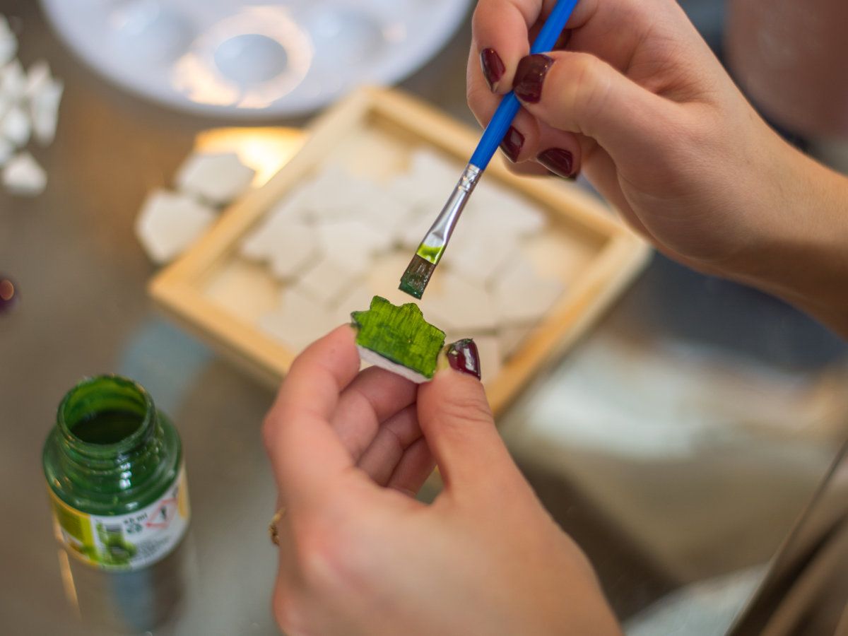 Een kleitegeltje groen schilderen met een fijn penseel