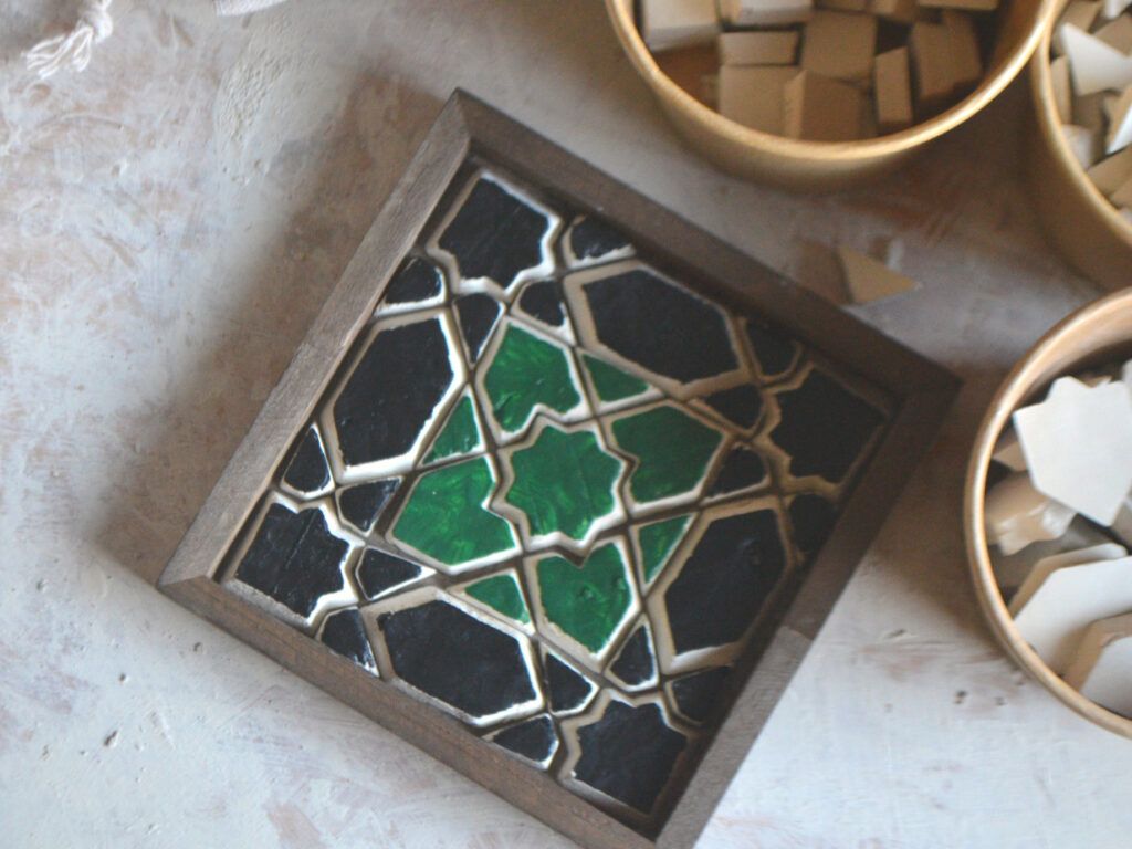 Een groen-zwarte geometrische onderzetter in een donker houten frame